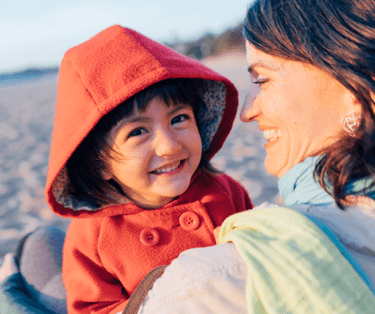 Smiling toddler being held by her happy mother