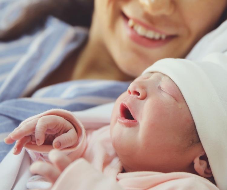 Newborn baby being held by smiling mom