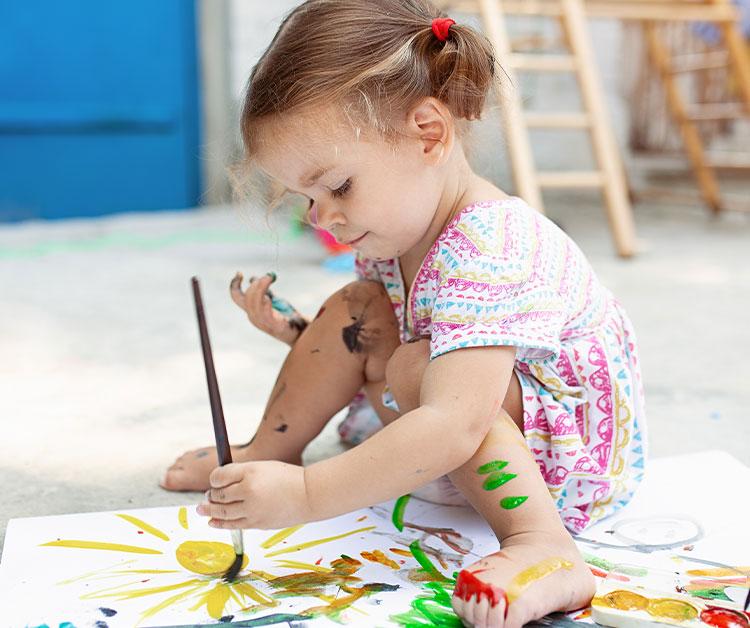Toddler sitting on the ground painting