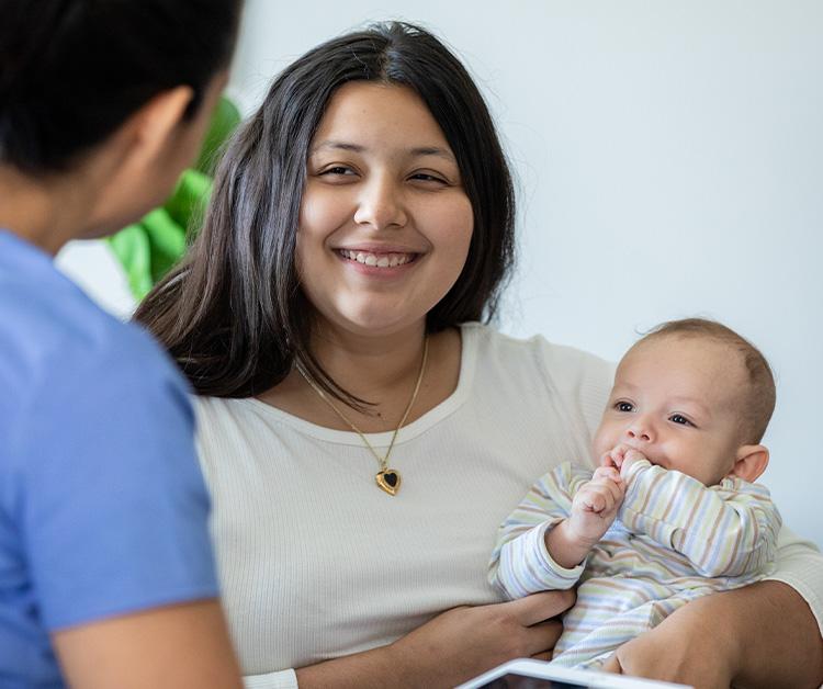 Mom holding her baby and speaking with a healthcare professional